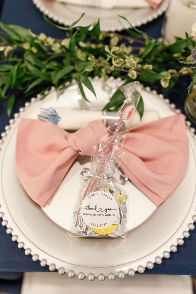 Place setting with a pink bow napkin and guest favor on a beaded charger—an affordable, stylish touch from an Austin wedding planner sharing wedding design ideas on a budget.
