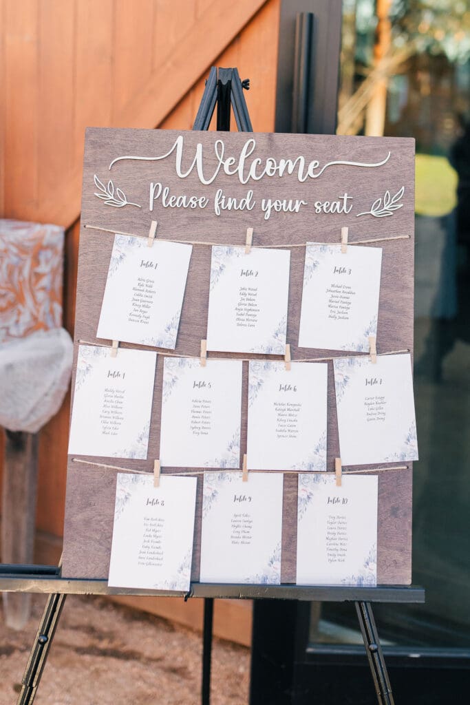 Rustic wood board with printed escort cards clipped on string, an affordable and charming seating chart option for wedding design ideas on a budget.
