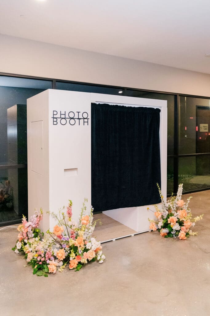 Maddie’s sleek white wedding photo booth setup with colorful floral arrangements, perfect for Hill Country weddings looking for interactive design ideas on a budget.