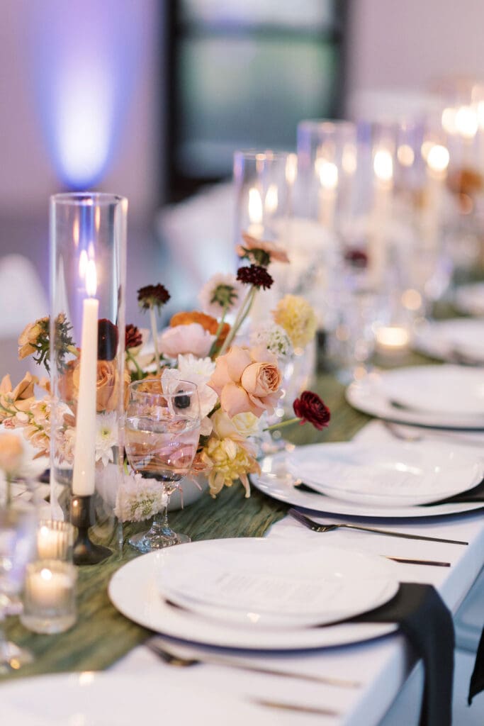 Close-up of romantic candlelit centerpiece with blush and burgundy florals—showcasing how lighting transforms wedding design on a budget.